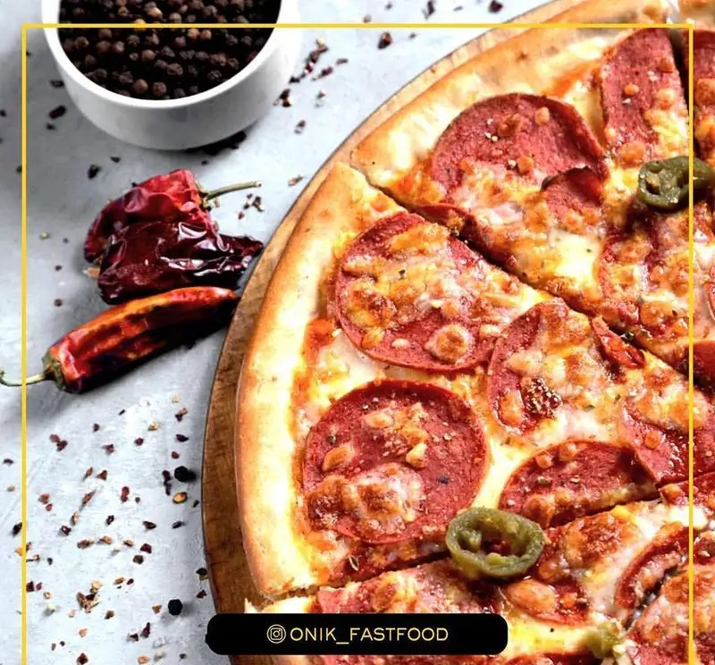 پیتزا پپرونی داغ و خوشمزه فست فود اونیک با چاشنی‌های معطر فلفل و چیلی؛ غذای آماده‌ای جذاب برای تجربه طعمی تند و به یادماندنی.