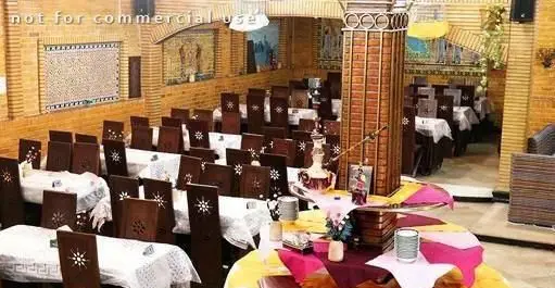 سفره خانه سنتی آق بانو: فضای داخلی دلنشین با دکوراسیون اصیل ایرانی، چیدمان منظم میز و صندلی‌های چوبی و قلیان مرکزی.