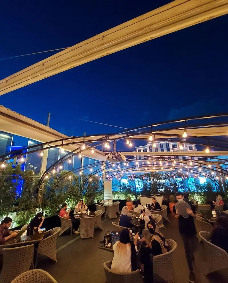 نمایی زیبا از فضای باز رستوران بنلی لانژ در شب، با مشتریان در حال صرف شام و لذت بردن از محیط دلنشین و نورپردازی جذاب.