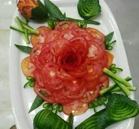 تزئین هنرمندانه سالاد در رستوران و سفره خانه سنتی دنج با گوجه فرنگی رز، خیار و هویج حکاکی شده، یک پیش غذای لوکس