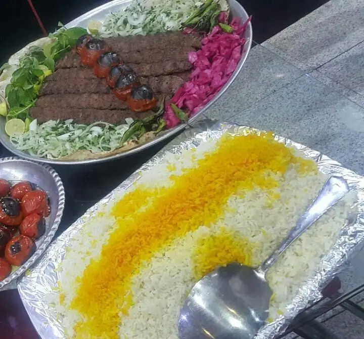 بشقاب بزرگ کباب کوبیده با گوجه کبابی، سبزیجات تازه و ترشی به همراه سینی برنج زعفرانی در رستوران سنتی دنج.