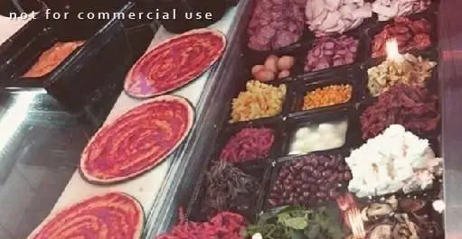 خط آماده‌سازی پیتزا در رستوران ایتالیایی کوزی کورنر: پایه‌های پیتزا و مجموعه‌ای وسیع از تاپینگ‌های تازه و باکیفیت برای مشتریان.