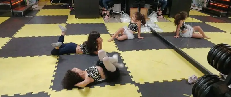 کودکان پرانرژی و شاد در حال تمرین رقص و فعالیت بدنی در محیط امن و جذاب باشگاه ورزشی گلایل.