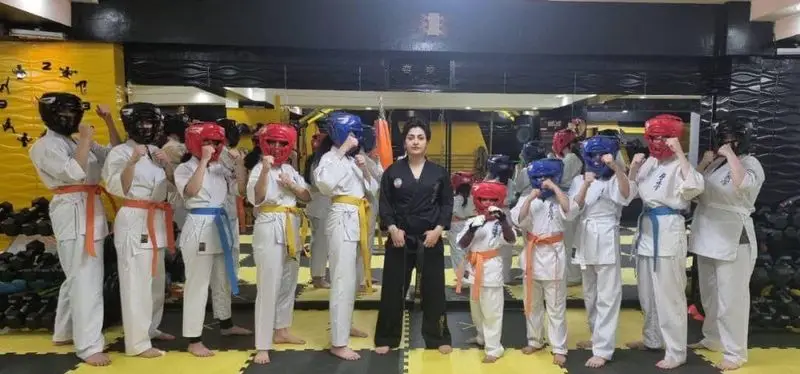 هنرجویان و مربی باشگاه ورزشی گلایل در حال آموزش کاراته و دفاع شخصی برای بانوان و کودکان با تمرینات منظم در محیطی حرفه‌ای