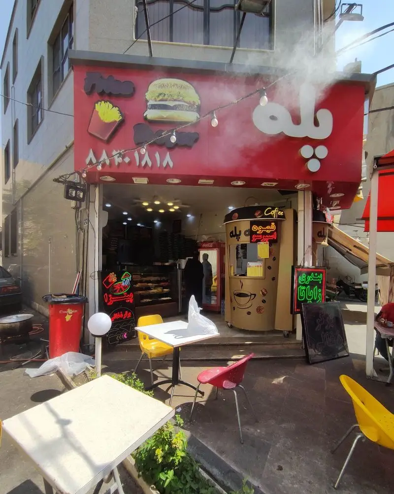 نمایی از فست فود پله در تهران با تابلوی همبرگر و سیب زمینی، فضای باز دلنشین و غرفه قهوه اسپرسو. ساندویچ بندری و ژاپاتا.