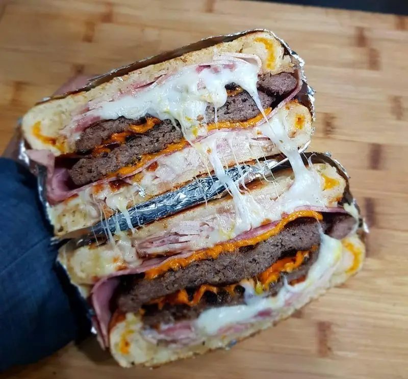 ساندویچ غول‌پیکر و پرملات گزینگ برگر با چندین لایه همبرگر، ژامبون، پنیر ذوب‌شده کشسان و سس مخصوص. تجربه‌ای لذیذ از Gzing Burger.