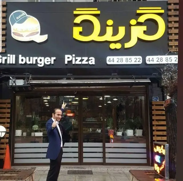 نمای بیرونی جذاب فست فود گزینگ برگر، با تابلوی درخشان و لوگوی برگر، ارائه دهنده انواع گریل برگر و پیتزای لذیذ. شماره تماس نیز در تابلو قابل مشاهده است.