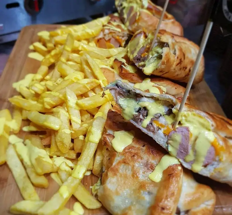 ساندویچ‌های ویژه گزینگ برگر با هات‌داگ، گوشت، پنیر و سس غلیظ در نان، همراه سیب‌زمینی سرخ‌کرده و سس پنیری. یک غذای لذیذ و کامل.