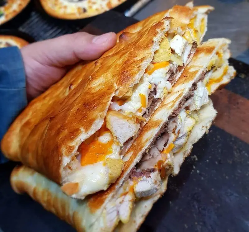 ساندویچ پرملات و داغ گزینگ برگر، حاوی تکه‌های مرغ، گوشت لذیذ، پنیر ذوب‌شده و نان طلایی برشته، انتخابی عالی برای فست فود.