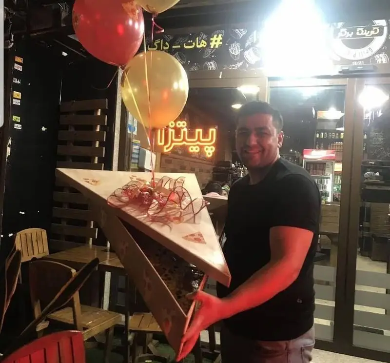 مشتری خوشحال در فست فود گزینگ برگر، جعبه پیتزای مثلثی زیبا را همراه با بادکنک‌های جشن به عنوان هدیه گرفته است.