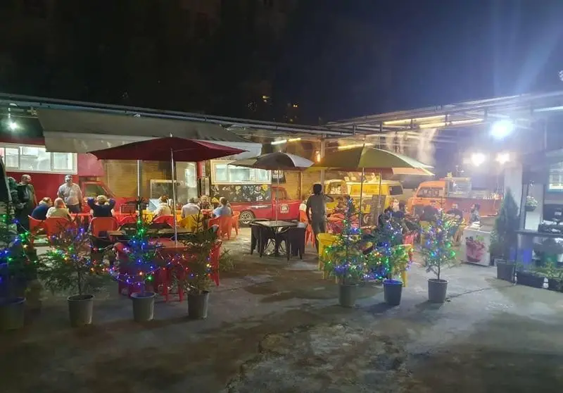 کارفودلند: فودکورت فضای باز شبانه با فودتراک‌های متنوع، میز و صندلی‌های شلوغ و چراغ‌های رنگی برای تجربه‌ای دلنشین.