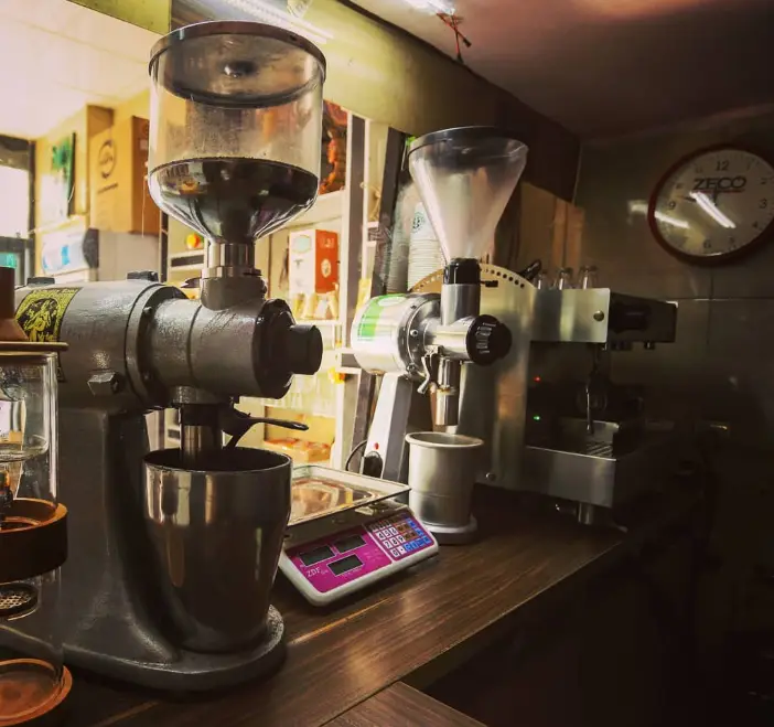 تصویر پیشخوان قهوه یویو با دستگاه‌های آسیاب قهوه، اسپرسو ساز و ترازو. نمایی از تجهیزات آماده سازی قهوه در کافی شاپ.