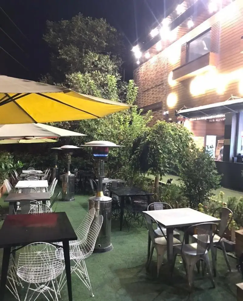 تصویری از فضای دلنشین و زیبای بیرونی رستوران سرزمین سوخاری در شب، مجهز به چترها، میز و صندلی راحت و گرماتاب برای پذیرایی عالی.