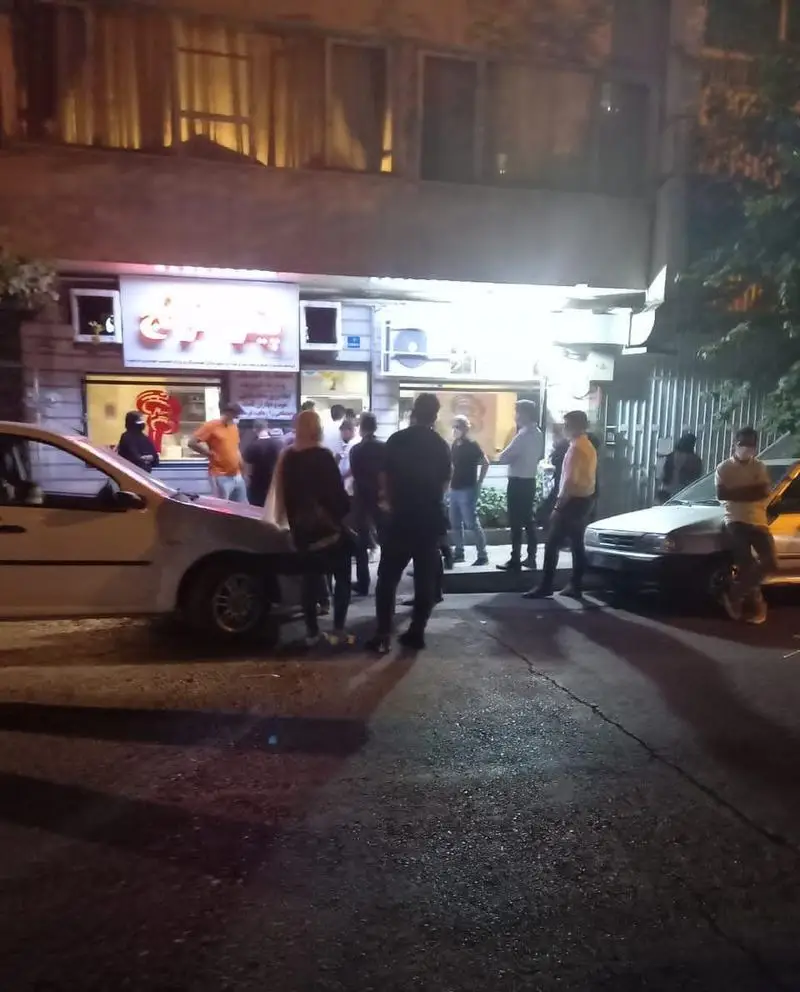 نمایی از فست‌ فود ترنج در شب، با حضور مشتریان و خودروها در خیابان، یک محیط پرجنب‌وجوش و دلپذیر برای غذا