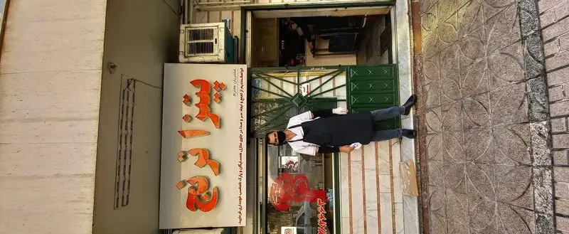 فست‌فود ترنج: نمای بیرونی مغازه با کارمند در حال خدمت‌رسانی و تابلوی بزرگ «ترنج» حاوی اطلاعیه برای مشتریان گرامی.