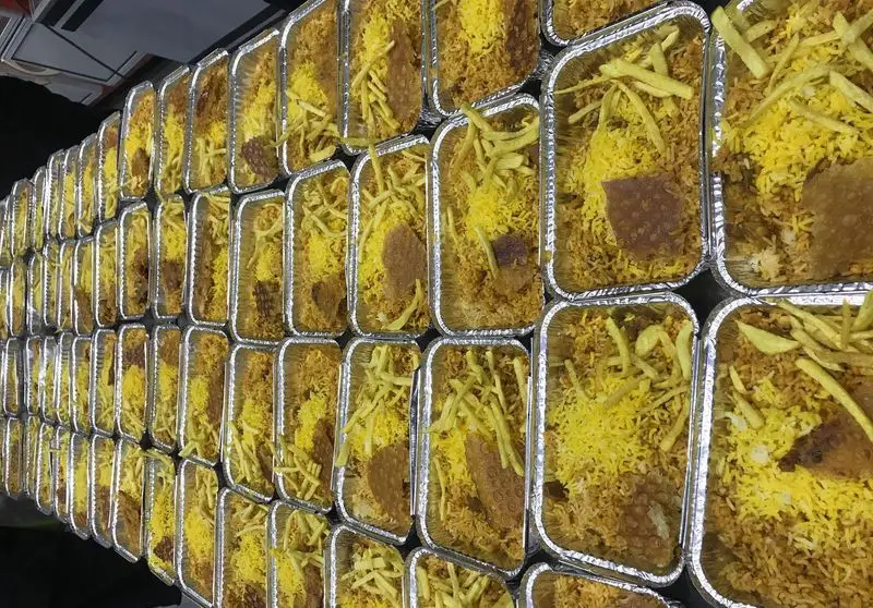 آماده‌سازی و بسته‌بندی غذاهای کترینگ رستوران تأیید: برنج زعفرانی و سیب‌زمینی سرخ‌کرده در صدها ظرف آلومینیومی.