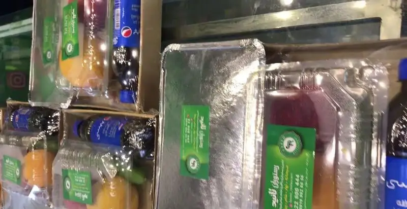 بسته‌بندی‌های متنوع رستوران تأیید: غذا در ظروف فویلی، آبمیوه‌های تازه و بطری‌های پپسی. آماده برای سفارش و ارسال.