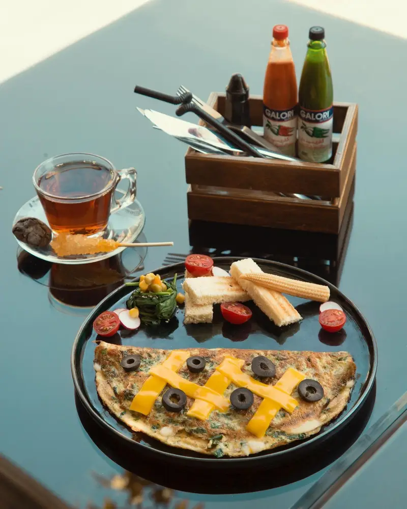 صبحانه کامل کافه ماها شامل املت سبزیجات با پنیر و زیتون، نان تست، چای و مخلفات تازه. منوی دلچسب صبحانه در کافه.