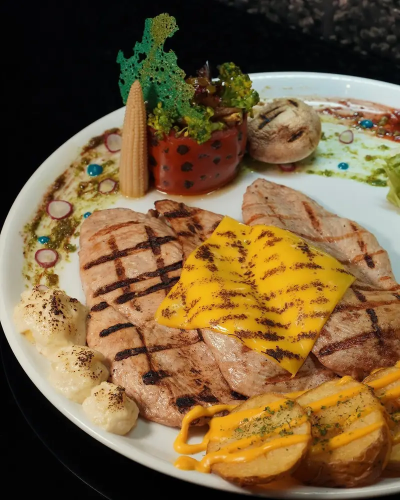 غذای اصلی کافه ماها: فیله مرغ گریل شده با پنیر، سیب‌زمینی برشته، فلفل دلمه‌ای شکم‌پر و سبزیجات تازه متنوع.