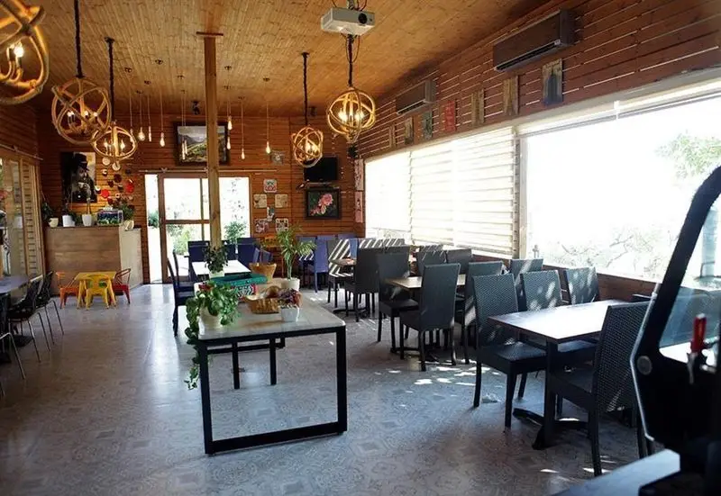 تصویری از فضای داخلی بزرگ و دنج کافه و رستوران امیر شکلات دارآباد با دیوارهای چوبی، نورپردازی مدرن، میز و صندلی‌های متنوع و محیطی آرامش‌بخش برای مشتریان.