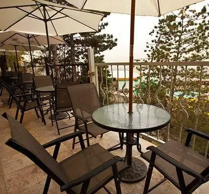 تراس دلنشین امیر شکلات دارآباد با میز و صندلی‌های شیک و چترهای سایبان، مکانی عالی برای لذت بردن از قهوه و منظره.