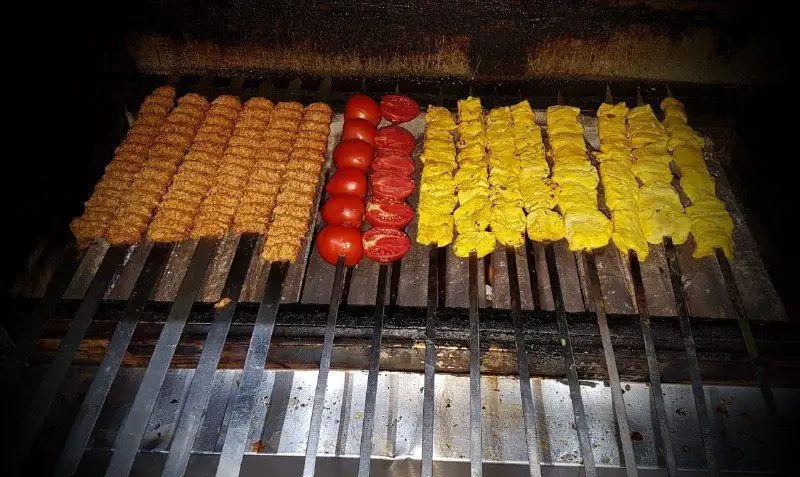 تهیه غذای آهنگ: کباب کوبیده و جوجه کباب زعفرانی تازه همراه با گوجه کبابی روی منقل، آماده برای سفارش.