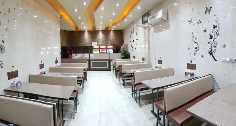 نمایی از فضای داخلی رستوران تهیه غذای آهنگ، با میز و صندلی‌های مرتب و دکوراسیون مدرن، محیطی دلنشین برای سرو غذا و پذیرایی.