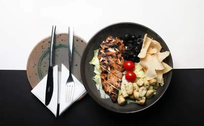 منوی کافه رستوران رپتور: سالاد مرغ گریل، شامل سینه مرغ گریل، کاهو، زیتون، گوجه گیلاسی و نان ترد. انتخابی سالم و لذیذ.