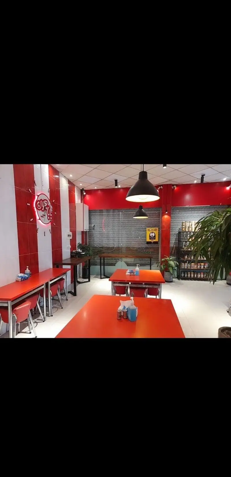 فضای داخلی فست فود بابا جون نارمک با دیوارهای راه راه قرمز و سفید، میزهای غذاخوری مدرن و نورپردازی جذاب، محیطی دلپذیر.