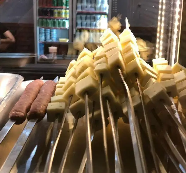 سیخ‌های آماده کباب از پنیر مکعبی و سوسیس تازه در جگرکی پاتوق، چیدمان شده و آماده برای کباب شدن و سرو به مشتریان.