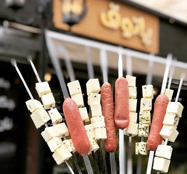 سیخ‌های کباب سوسیس و پنیر مکعبی با سبزیجات، آماده برای کباب شدن در جگرکی پاتوق. طعم اصیل و فراموش نشدنی.