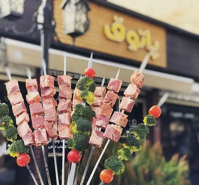 سیخ‌های جذاب جگر، بروکلی و گوجه‌گیلاسی تازه در مقابل تابلوی جگرکی پاتوق، آماده برای کباب کردن و سرو.