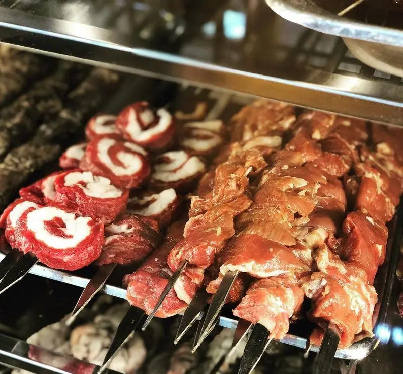 انواع سیخ کباب‌های لذیذ و تازه در جگرکی پاتوق: شامل کباب رول پیچ گوشت و دنبه و گوشت‌های مزه‌دار شده، آماده برای طبخ و سرو.