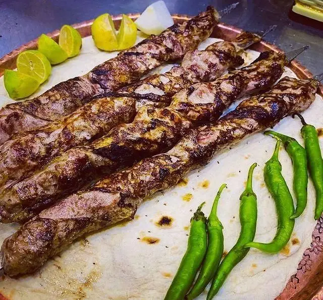 چند سیخ کباب کوبیده خوشمزه جگرکی پاتوق، با چاشنی لیمو تازه و فلفل سبز، سرو شده روی نان سنتی داغ. غذای اصیل ایرانی.