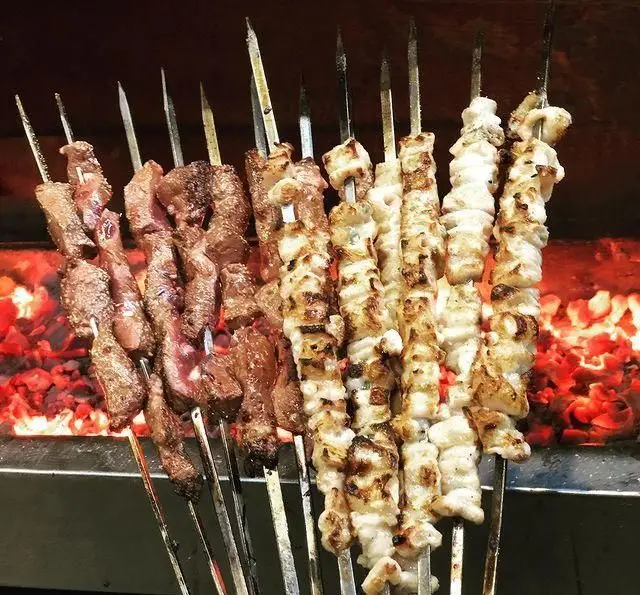 انواع سیخ‌های کباب جگر، دل و جوجه در حال پخت بر روی آتش ذغال گداخته در فضای دلنشین جگرکی پاتوق.