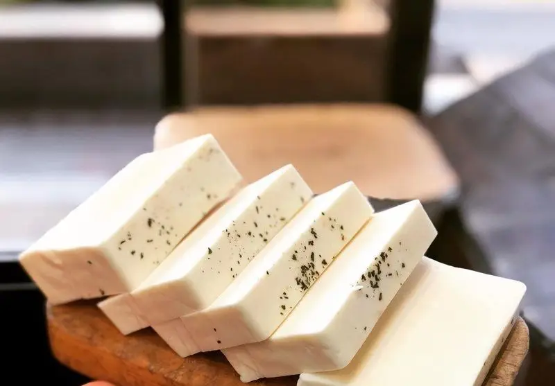 پنیر سفید تازه با سبزیجات معطر، چیده شده بر روی تخته چوبی، یک پیش غذای خوشمزه و مناسب برای تجربه در جگرکی پاتوق.