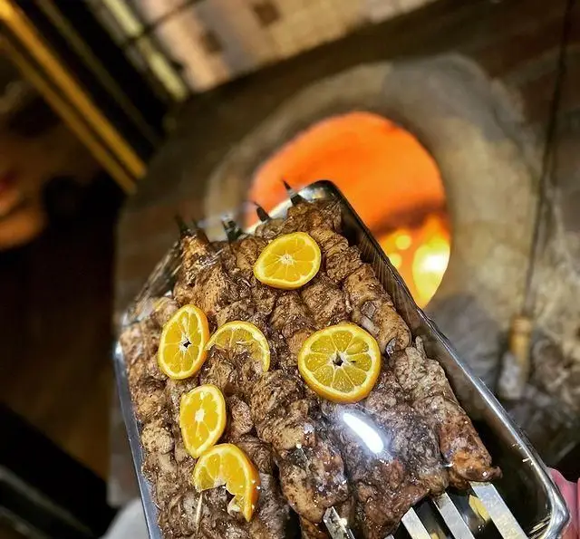 سیخ‌های کباب جگر و جوجه تازه و طعم‌دار شده با پرتقال، آماده پخت در تنور داغ جگرکی پاتوق، تجربه‌ای لذیذ از غذای اصیل.