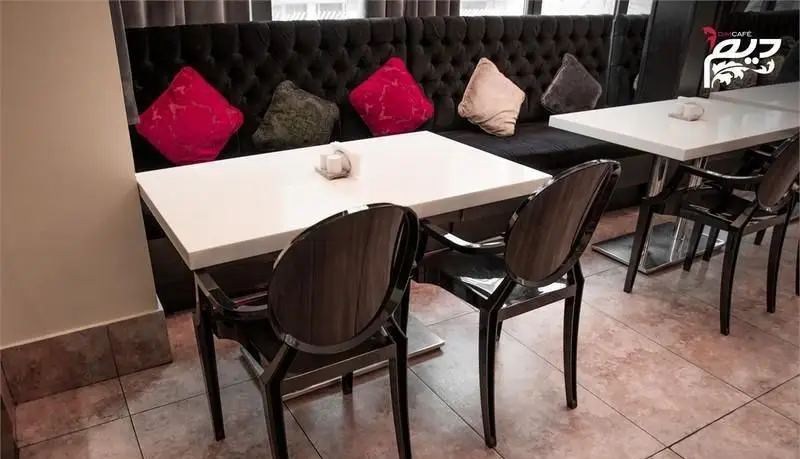 فضای داخلی مدرن و دنج رستوران دیم، مناسب قرارهای دوستانه و کاری، با مبلمان سیاه، کوسن‌های رنگارنگ، میزهای سفید تمیز و صندلی‌های شیک.