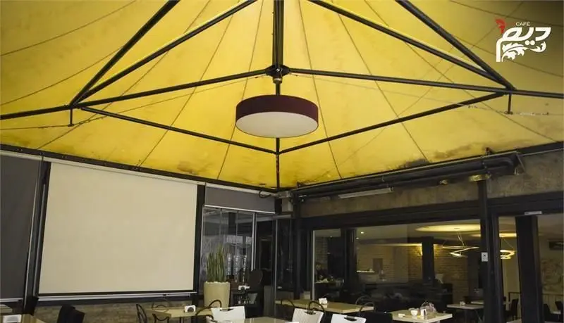 نمایی از سقف پارچه ای زرد و طراحی داخلی مدرن کافه رستوران دیم، با نورپردازی زیبا و محیطی دنج برای لحظاتی خاطره‌انگیز.