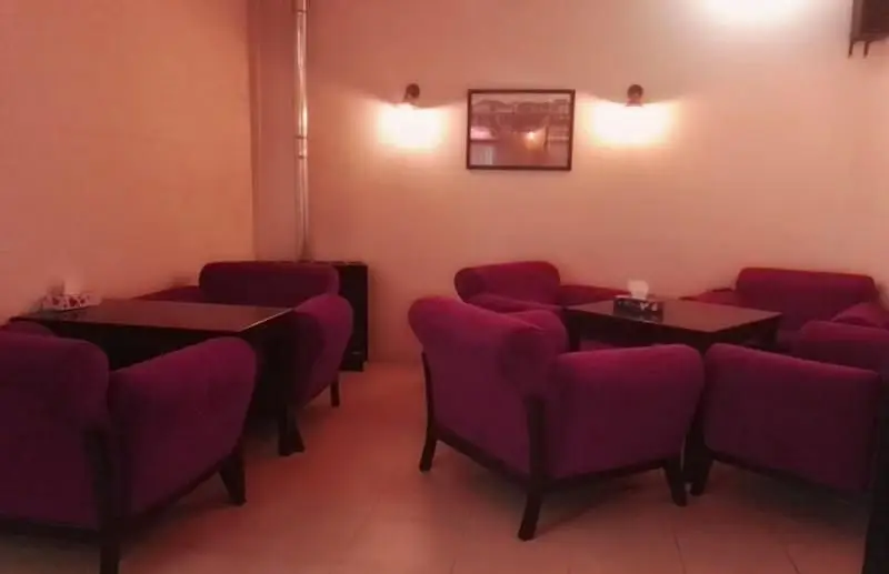 فضای داخلی رستوران فرنگی ایوان با چیدمان دنج و شیک، شامل مبلمان راحتی بنفش و میزهای تیره، با نورپردازی گرم، محیطی آرام و دلنشین برای پذیرایی.