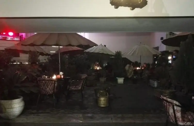 تصویری از فضای باز و دنج رستوران فرنگی ایوان در شب، با چترها، نورپردازی گرم، میز و صندلی‌های شیک برای تجربه‌ای لذت‌بخش.