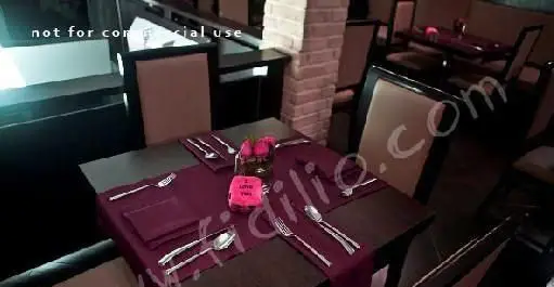 دکوراسیون داخلی لوکس رستوران لئون: میز شامی رمانتیک با رانر زرشکی، سرویس قاشق و چنگال استیل، گل رز و کارت I love you برای لحظات خاص.