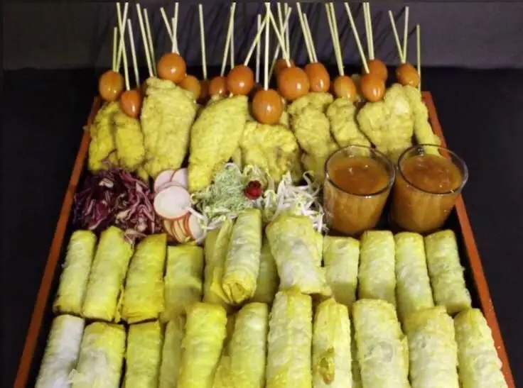 سینی متنوع غذای آسیایی رستوران الین سوشی شامل اسپرینگ رول‌های طلایی، ساتای مرغ و گوجه گیلاسی به همراه سس‌های مخصوص، آماده برای سرو.