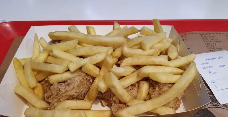 یک وعده غذایی فست فود از مرغ سوخاری ترد و سیب زمینی سرخ کرده فراوان در فود کورت بزرگ ایران مال تهران.