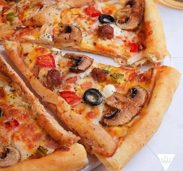 تصویری از برش‌های طلایی پیتزا سیب ۳۶۰ با تاپینگ‌های قارچ، زیتون، فلفل و پنیر ذوب شده. طعمی بی‌نظیر و خوشمزه از پیتزا سیب ۳۶۰.