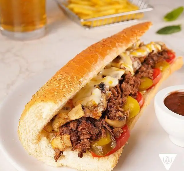 ساندویچ چیز استیک لذیذ و پرملات پیتزا سیب ۳۶۰: گوشت تازه، پنیر آب شده، قارچ، فلفل و گوجه. در کنار سیب زمینی سرخ کرده و نوشیدنی گوارا.