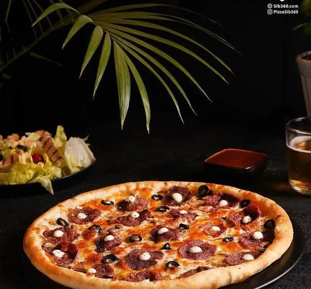 عکس پیتزا سوسیس و زیتون لذیذ سیب ۳۶۰ همراه با سالاد تازه و نوشیدنی خنک، انتخابی ایده‌آل برای سفارش آنلاین و حضوری از پیتزا سیب ۳۶۰.