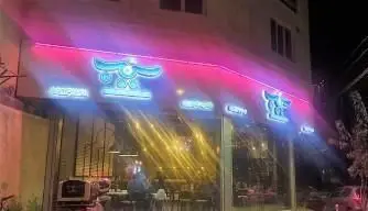 شب، نمای بیرونی شعبه پیتزا سیب ۳۶۰ با تابلوی نئونی چشمگیر، نورپردازی مدرن و جلوه‌ای دعوت‌کننده برای تجربه بهترین پیتزا و فست فود.