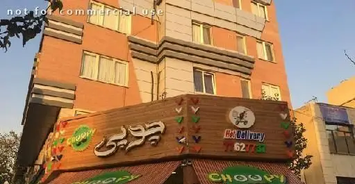 نمای بیرونی فست فود چوپی برگر، با تابلوی فارسی و انگلیسی و خدمات دلیوری داغ، در پس زمینه ساختمانی شهری.