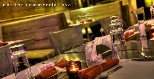 فضای دلنشین رستوران دارچین با چیدمان زیبای میزها، شامل لیوان‌های آب، دستمال‌های سفره و شمعی روشن برای آرامش.